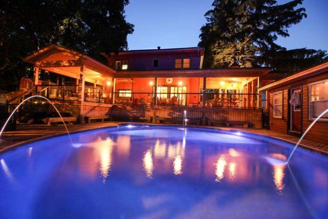 backyard with lit pool and covered deck at night