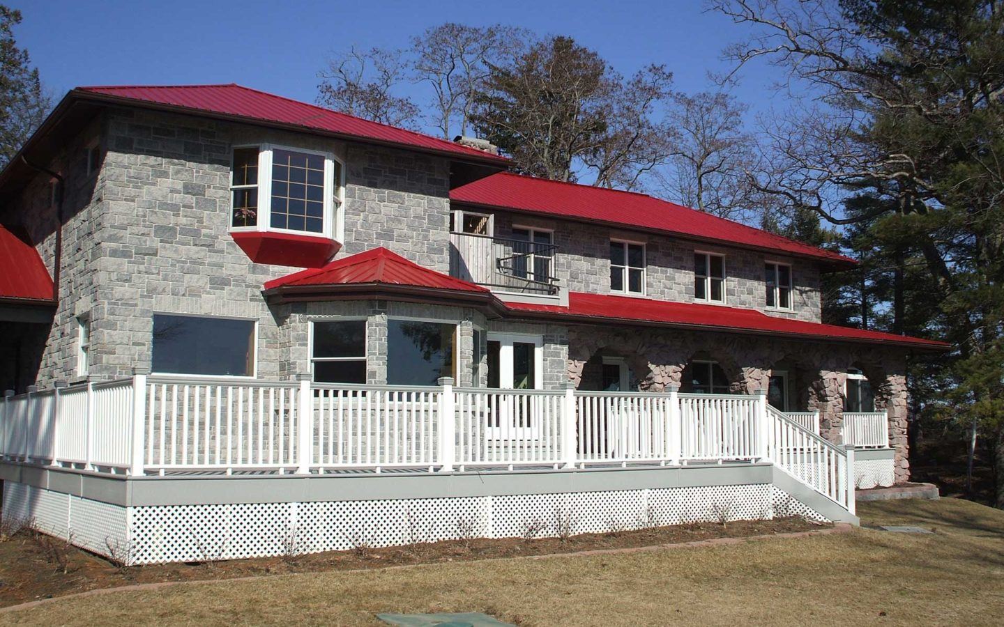 exterior photo of a prey stone house with red tin roof