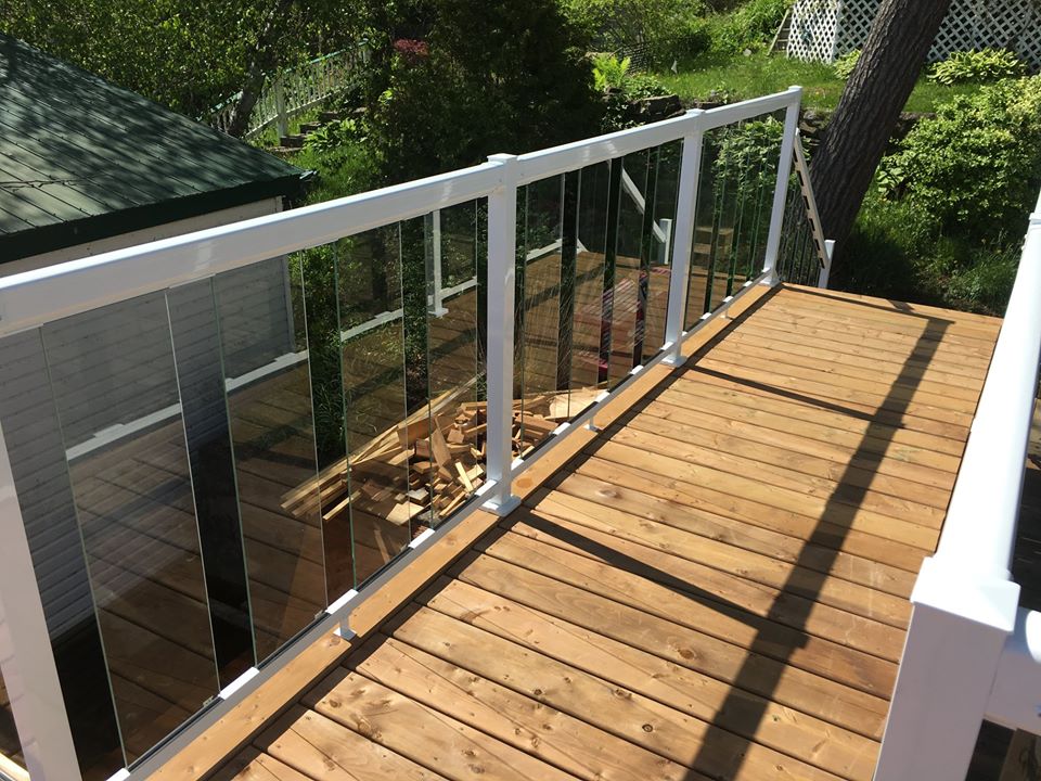 a wooden deck with a glass fence with white railings