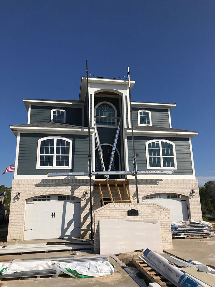 a three story home with two garages and blue siding