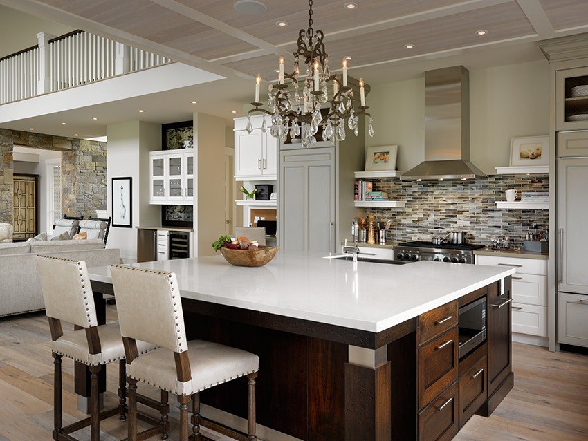 a candle stick chandelier above a large kitchen island with a white countertop