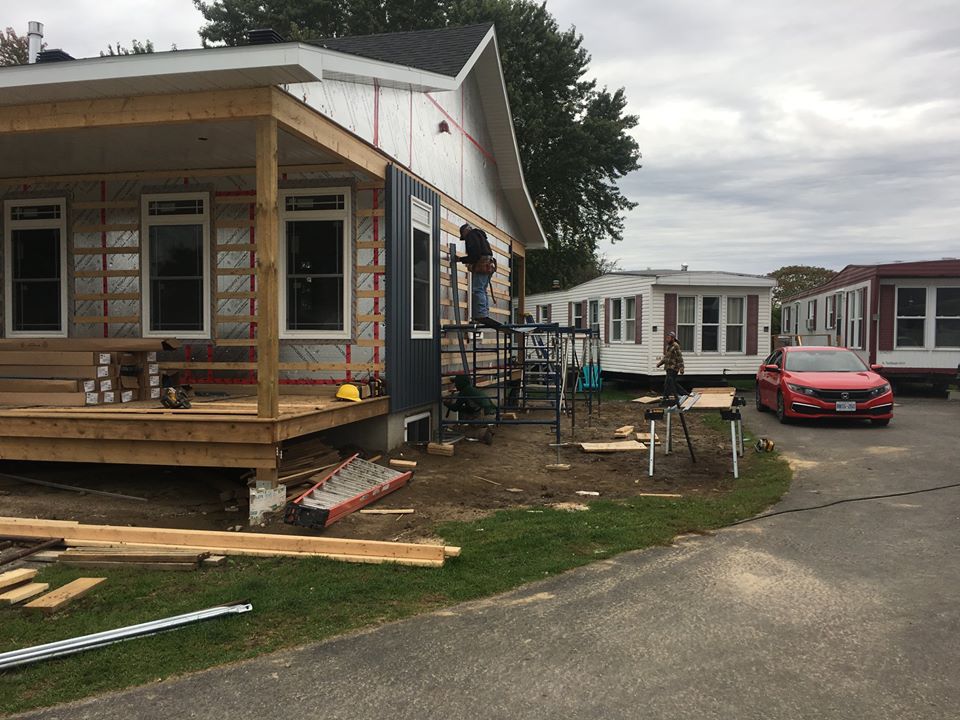 a man standing on a ladder putting siding on a home under construction