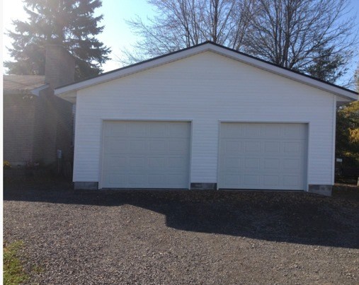 a white two car garage with a gravel driveway