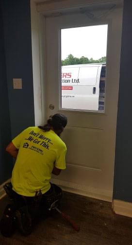 man in yellow shirt bent over installing a door