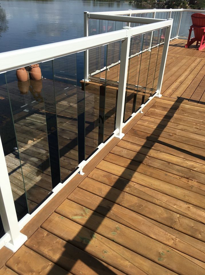 a wooden deck with a glass fence and white railing